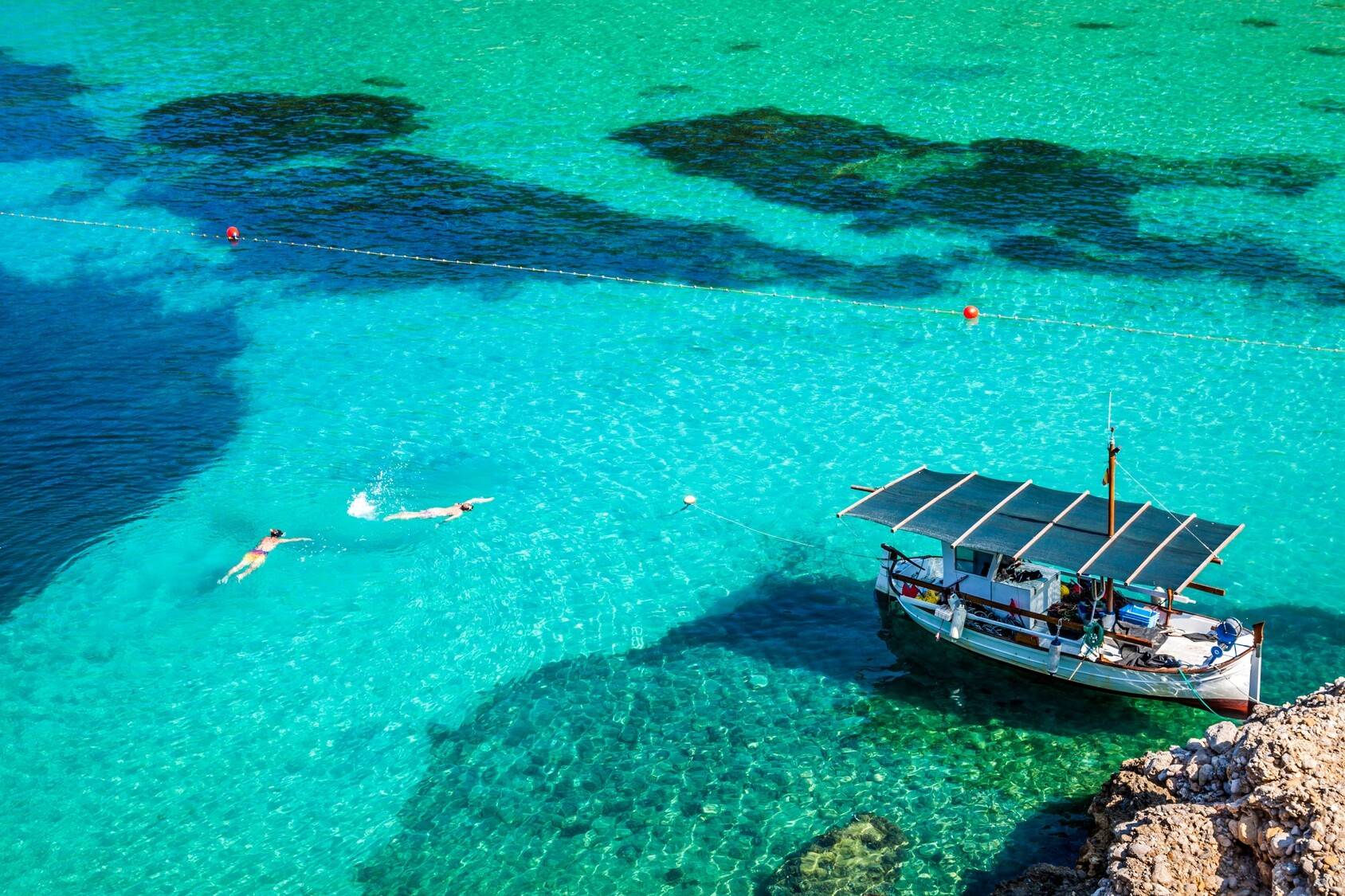 Fischerboot im türkisfarbenen Meer in Spanien